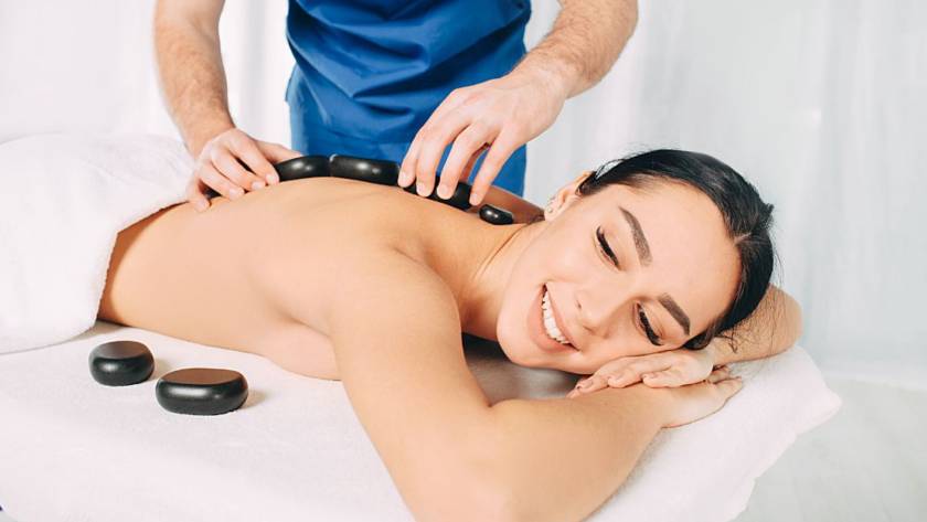female patient in massage table having a massage session with hot stones